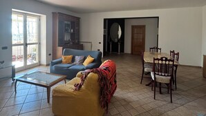 A spacious living room with a sofa, a coffee table, and a dining table with chairs. - Detached cottage among the pines of Sila (CS) (Rose)