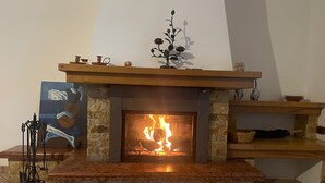 A fireplace with a stone surround, a mantel with decorative items, and a painting on the wall. - Detached cottage among the pines of Sila (CS) (Rose)