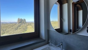 Een badkamer met een groot raam, een wastafel en een spiegel.