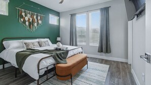 Ein Schlafzimmer mit Bett, einer Bank, einem Deckenventilator und Wanddekoration.