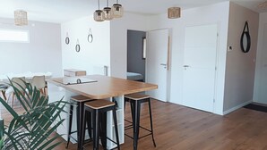 Een moderne keuken met een houten tafel, barstoelen, hanglampen en uitzicht op de aangrenzende eetruimte.