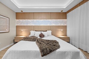 Un dormitorio con una cama grande, cabecera de madera, lámparas de noche y un aplique de pared.
