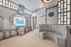 Una habitación temática de Star Wars con un panel de control, un área de estar circular y una pared con paneles de ventilación.