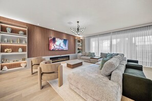 A modern living room with a flat-screen TV, a fireplace, a sofa, and a coffee table.