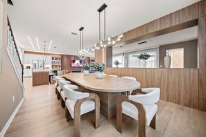 A modern kitchen with a central island, white chairs, and pendant lighting.