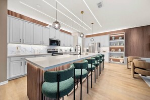 A modern kitchen with white cabinets, a central island with bar stools, and pendant lighting.