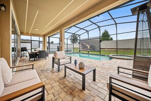 A covered patio with outdoor furniture, a pool, and a view of a tractor.