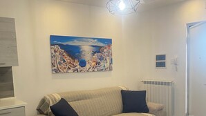 A modern living room with a beige sofa, two dark cushions, a wooden dining table, and a hanging light fixture. - Entire apartment with terrace, free parking, free wi-fi (Vico Equense)