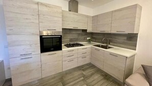 A modern kitchen with light wood cabinets, a built-in oven, a gas stove, and a stainless steel sink. - Entire apartment with terrace, free parking, free wi-fi (Vico Equense)