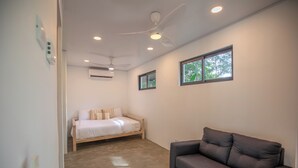 Une chambre moderne avec un lit en bois, un canapé foncé et un ventilateur de plafond.