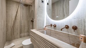 Une salle de bain moderne avec un lavabo en marbre, un grand miroir et un espace douche.