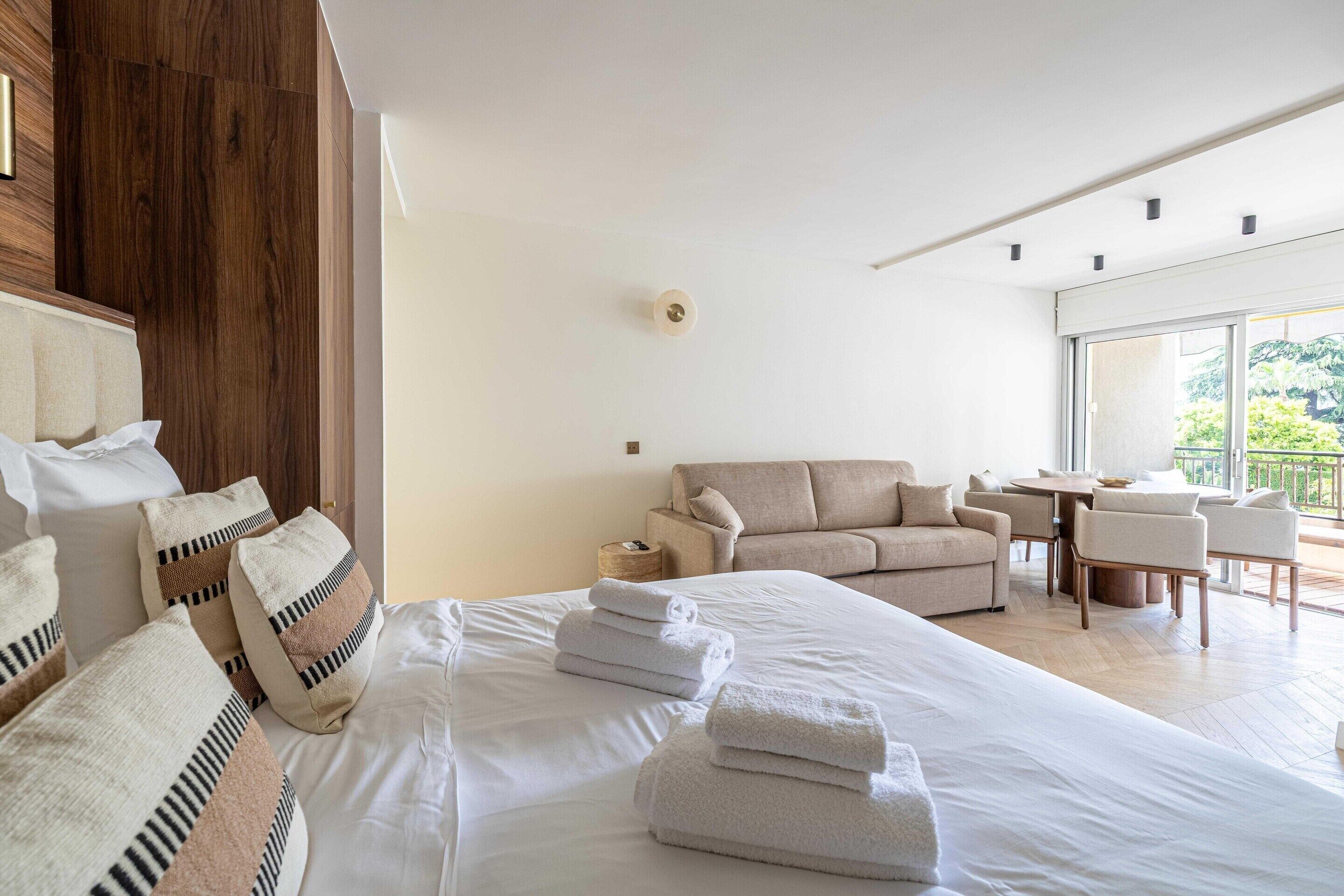 Una camera d'albergo con un letto grande, un divano, un tavolo da pranzo e vista sul verde.