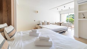 Une chambre d’hôtel moderne avec deux lits, un balcon et une vue sur la verdure.