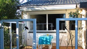 A patio with a table and chairs, a small garden area, and a house with a tiled roof. - Vacation home Holland, 2 -4 pers., sea, dog, gas fireplace, wifi  (Sint Maartensvlotbrug)