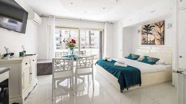 Quarto moderno com cama, escrivaninha e espaço de refeições.