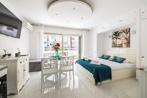 A modern bedroom with a bed, a desk, and a dining area. - Charming Studio - AC - 2P- Croisette Plage (Cannes)