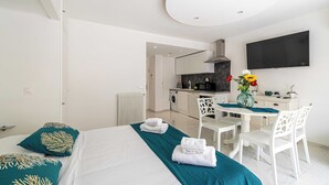 Quarto de hotel moderno com cama, escrivaninha e cozinha compacta.