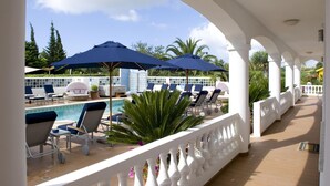 A poolside area with lounge chairs and umbrellas, a pool, and a view of the surrounding landscape. - Monte Laranja Apt in Lagos (Lagos)