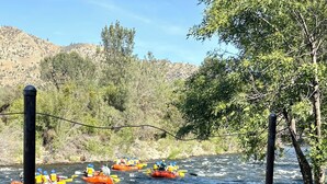 A river with three orange rafts and a person holding a can.
