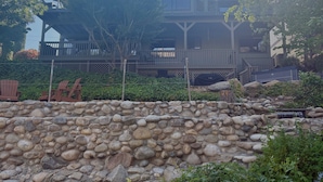 A stone wall with a wooden deck and a building in the background.