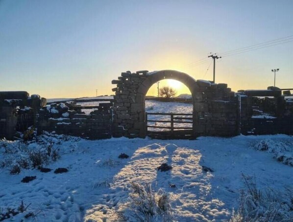 A stone archway leading into a snowy landscape with a clear sky.