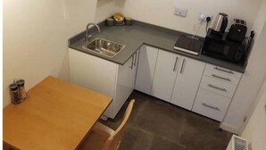 Una cocina compacta con un lavamanos, encimera y armarios.
