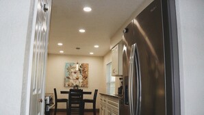 A kitchen with a stainless steel refrigerator, white cabinets, and a dining table with chairs. - Orlando 3 Bedroom Close to Disney (Orlando)
