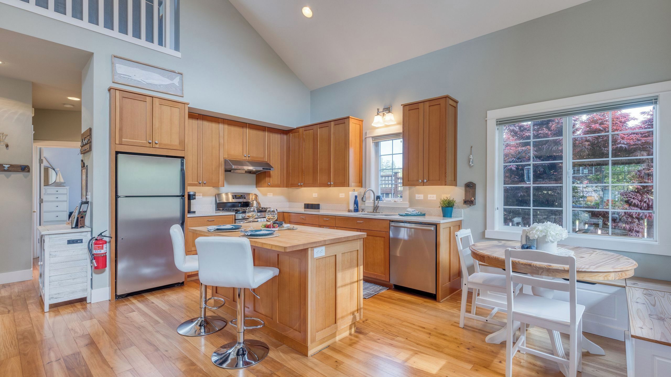Una cocina moderna con armarios de madera, electrodomésticos de acero inoxidable y una isla central con taburetes de bar.