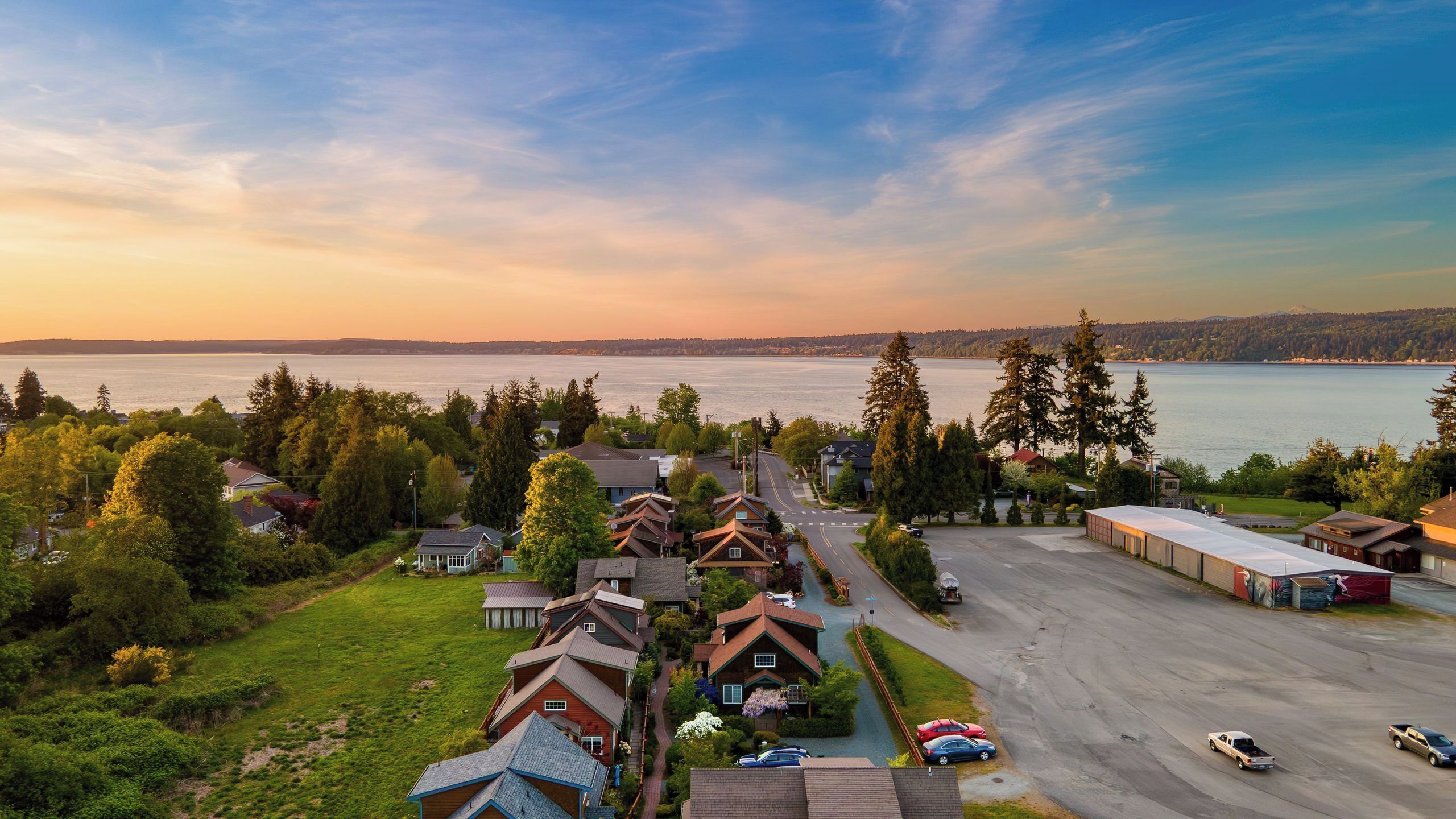 A residential area with houses, a parking lot, and a view of a lake.