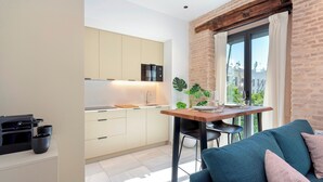 A modern kitchen with a built-in oven, a dining area with a table and chairs, and a view of the city through a large window.