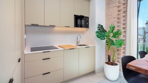 Eine moderne Küche mit integriertem Mikrowellenherd, Spüle und einer Arbeitsplatte mit Schneidebrett. Neben der Spüle steht ein Blumentopf und es gibt einen Essbereich mit Tisch und Stühlen.