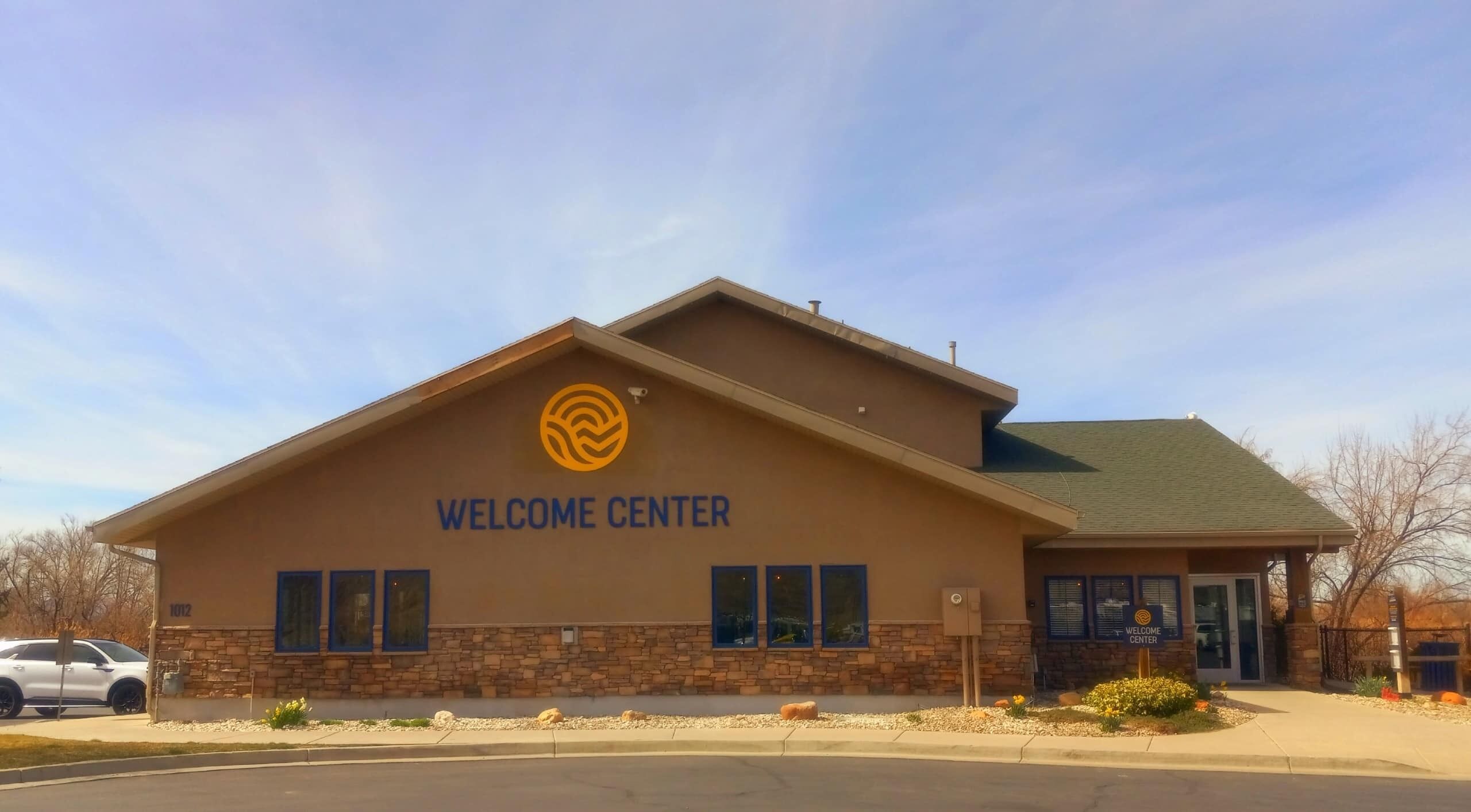 A building with a 'Welcome Center' sign, a stone facade, and a green roof.