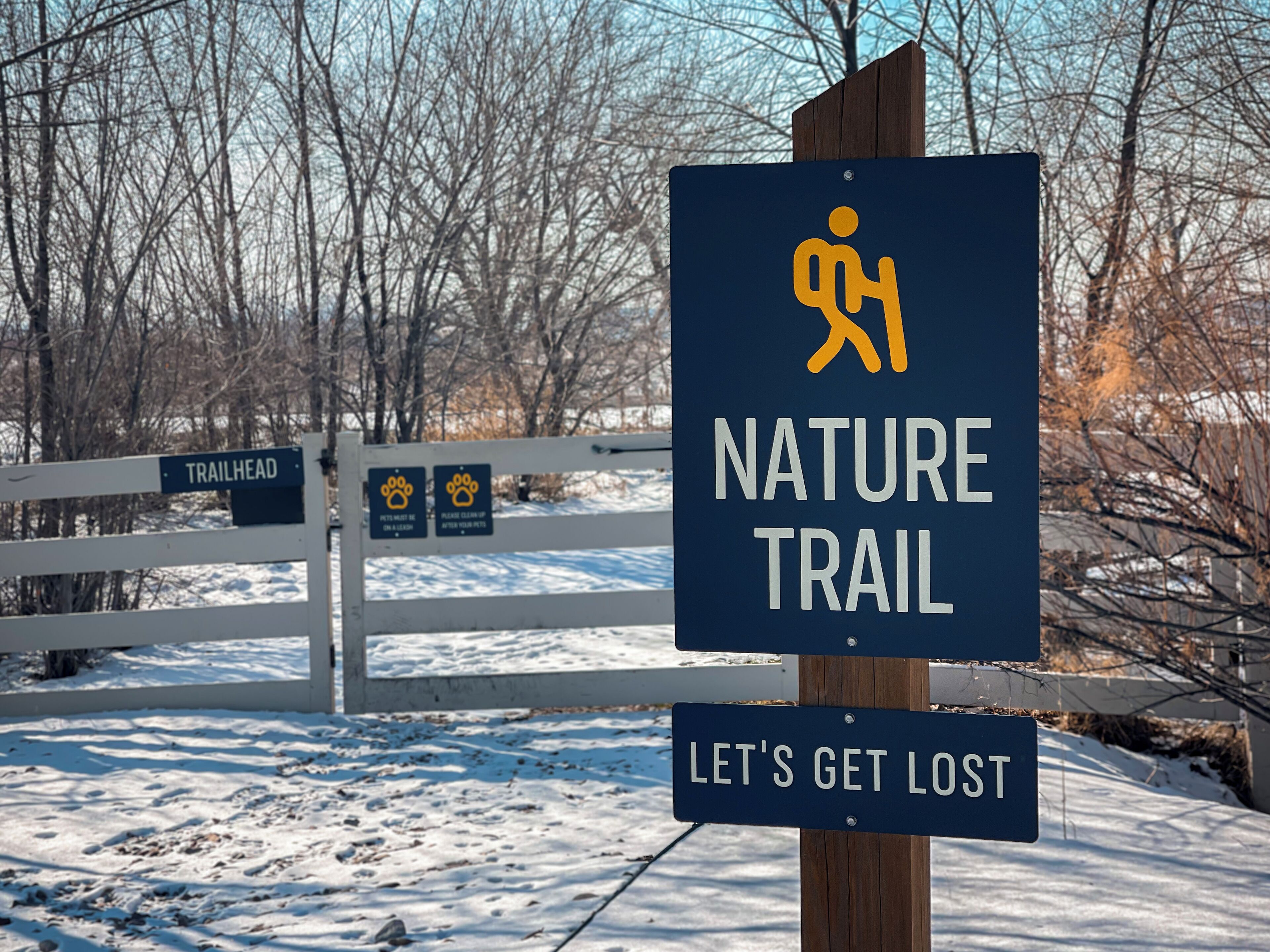 Schild für einen Naturpfad mit einem Symbol einer wandernden Person und dem Text „NATURE TRAIL“ und „LET'S GET LOST“.