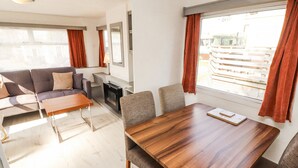 Een moderne woonkamer met een zithoek, een houten eettafel en een open haard.