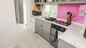 Een kleine keuken met een magnetron, broodrooster, spoelbak en een afdruiprek.