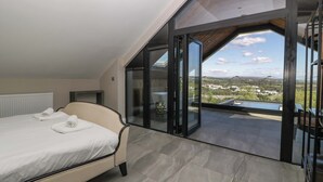 A bedroom with a bed, a radiator, and a view of a landscape through a glass door. - Forest Lodge (Pontyclun)