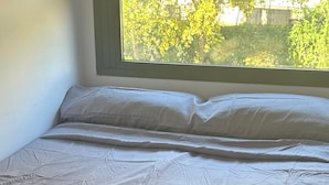 A neatly made bed with a beige bedspread and a folded gray towel on top. - Fast Latin Home (Seville)
