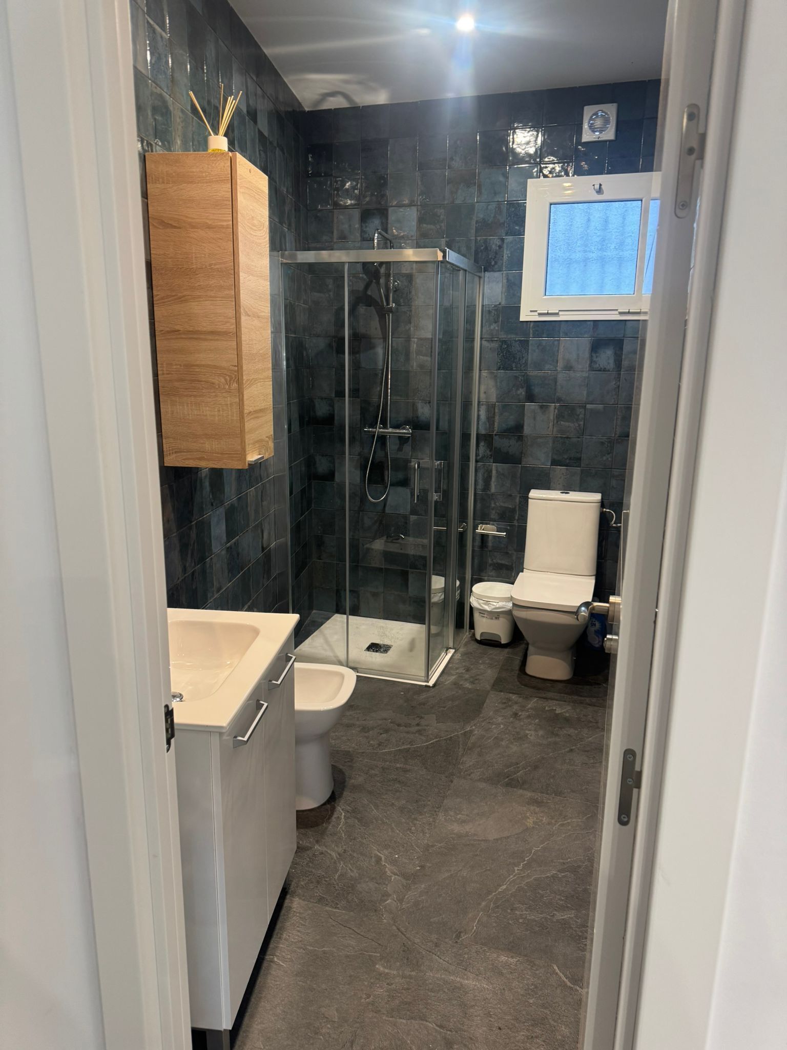 A modern bathroom with a glass-enclosed shower, a white sink, and a toilet.