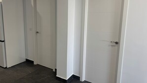 A hallway with white doors and a refrigerator on the left. - Fast Latin Home (Seville)