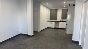 A spacious kitchen with white cabinets, a black countertop, and a built-in refrigerator. - Fast Latin Home (Seville)