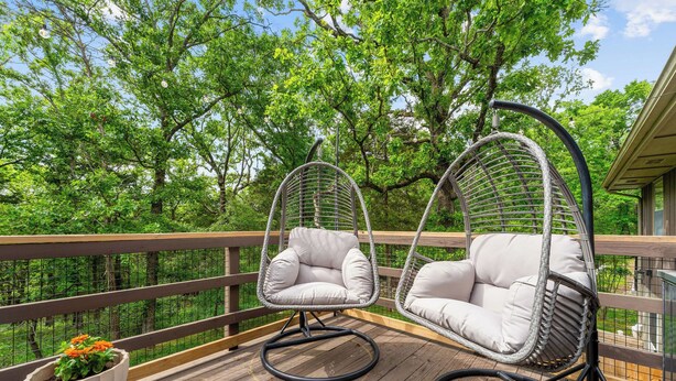 A wooden deck with two wicker swing chairs and a potted plant. - Private Pickleball Court, Sauna, Hot Tub, Heart of Branson, Sleeps 13! (Branson)