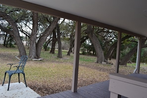 A covered outdoor area with a metal chair and a bench, surrounded by trees. - Jenkfarm Getaway
Your Home Away from Home (Nolanville)