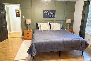 A bedroom with a large bed, two bedside tables with lamps, a wall-mounted artwork, and a door leading to another room. - Jenkfarm Getaway
Your Home Away from Home (Nolanville)