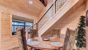 Ein Holzinnenraum mit einem runden Esstisch, Stühlen und einer Treppe.