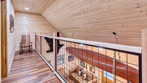 Ein Holzinnenraum mit schrägverdeckter Decke, Holzboden, gepolstertem Sitz und Metallgeländer.