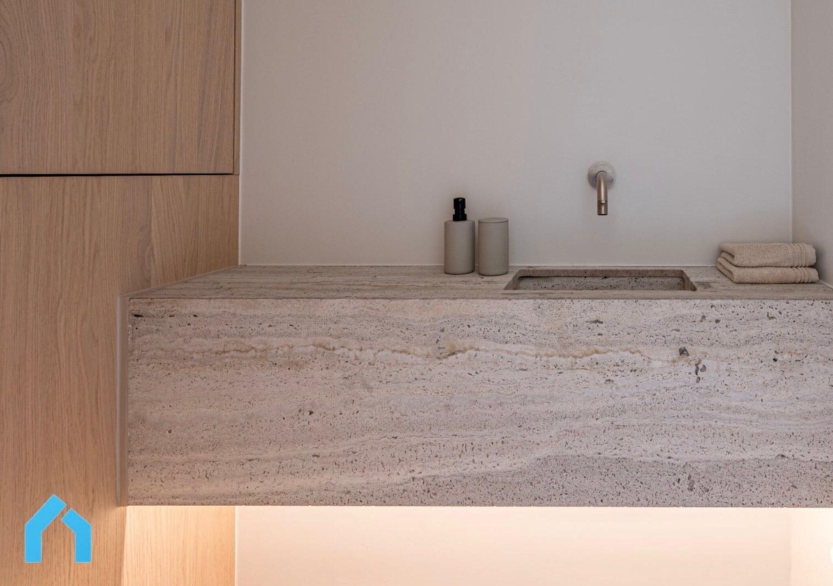 A bathroom with a marble countertop, a wooden cabinet, a sink with a faucet, and two cylindrical containers.