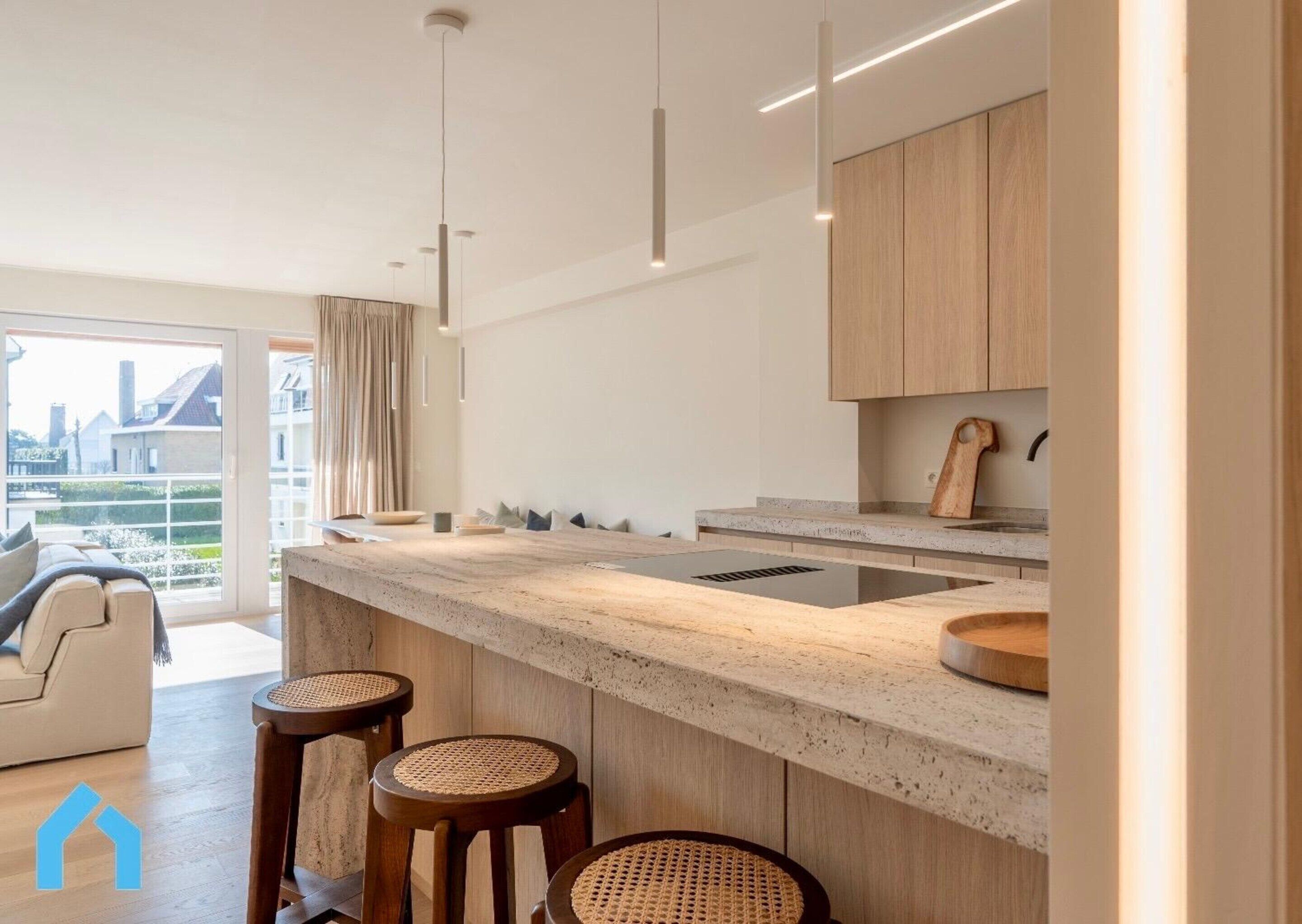 Une cuisine moderne dotée d’un grand îlot central, de meubles en bois et offrant une vue sur la ville.