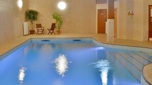 An indoor swimming pool with clear blue water, two wooden chairs, and potted plants. - Cottage in Devon With Private Hot Tub (Newton Abbot)
