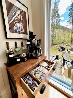 Un angolo caffè con una macchina da caffè, distributori di tè e un cassetto con cialde per caffè.