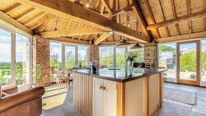 Una cocina amplia con una isla grande, vigas de madera y ventanas grandes que ofrecen vistas al exterior.